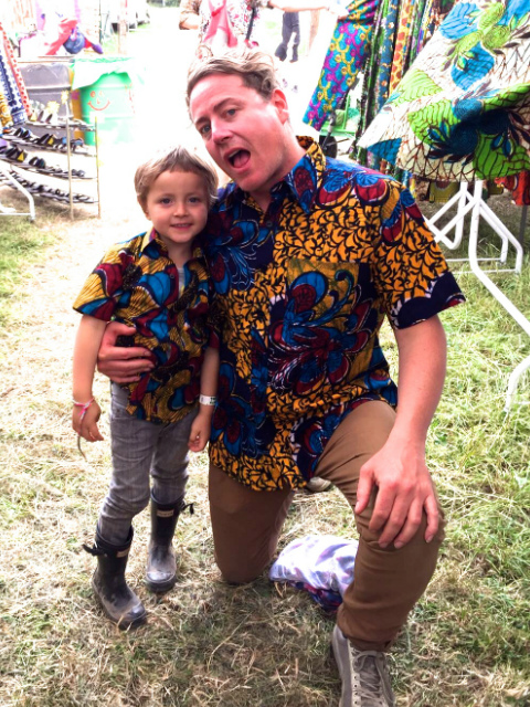 Father and son wearing matching Kitenge African print style shirts with short sleeves at Glastonbury Festival UK