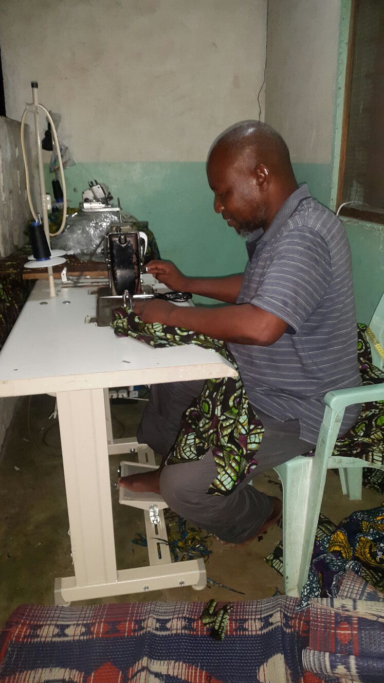Abdallah kitenge's main tailor working from his home with sewing machine