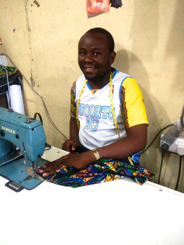 Kitenge tailor called Hassan with Singer sewing machine in shared workshop in Tanzania