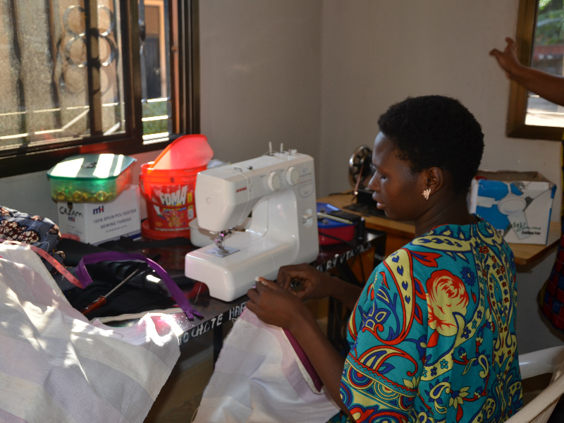 Abigail sewing in Kitenge tailor Betty's old workshop in Tanzania before expanding her business premises