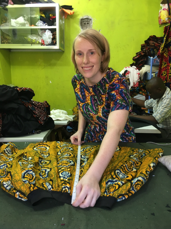 Kitenge founder Sian quality checking a newly handmade yellow African print skirt during production at our main tailors cutting table at his own workshop in Tanzania