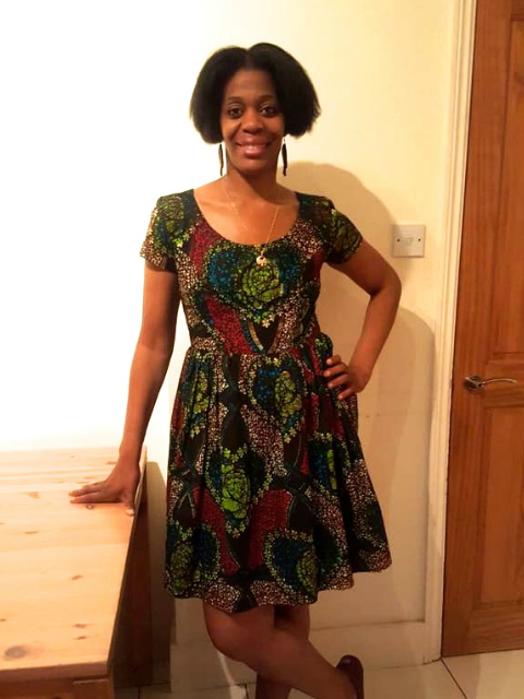 Kitenge customer wearing her African print dress fit and flare style with bold statement earrings