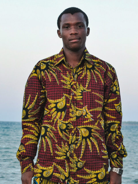 Men's Peacock African Print Long Sleeve Shirt worn by a model on the beach in Tanzania