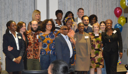 Kitenge Store founder Sian wearing an African print dress standing with her course mates at the School for Social Entrepreneurs Fellowship Graduation event at PwC offices in Central London