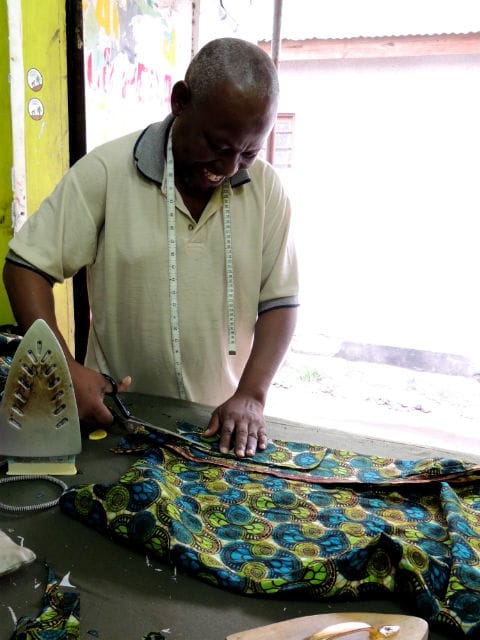 Kitenge Store Master Tailor hand cutting fabric to make an African print shirt in Tanzania