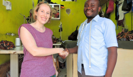 Sian and Hassan shaking hands outside Kitenge's main tailor's new workshop in Tanzania