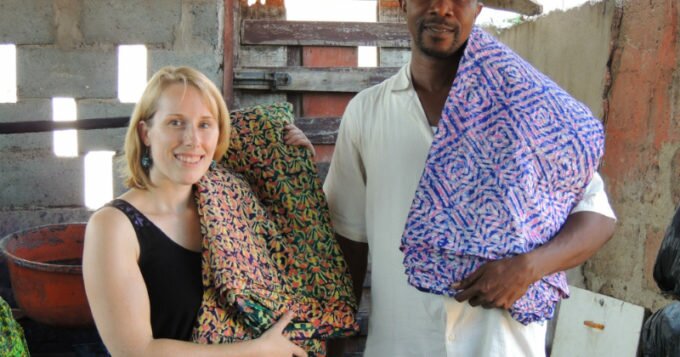Kitenge Store Founder Sian visited Daniel at his batik making workshop in Ghana West Africa holding two different finished colourful fabric designs used to make modern afrocentric clothing