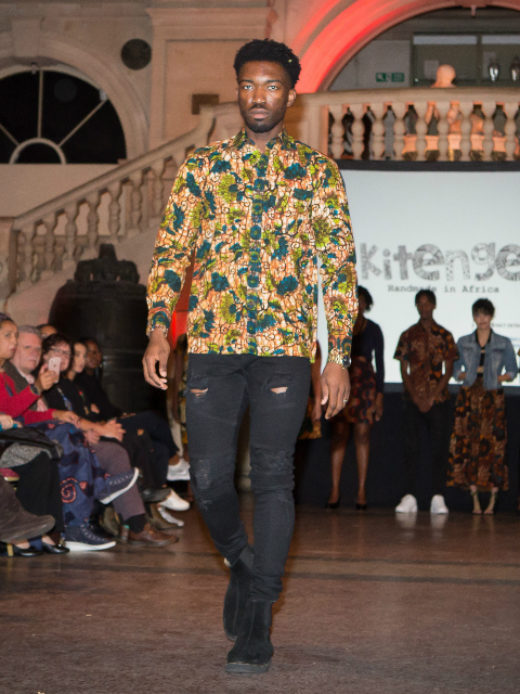 A male model wearing a green and blue floral African print long sleeve shirt at the Fabric Africa Fashion Show in Bristol Museum UK