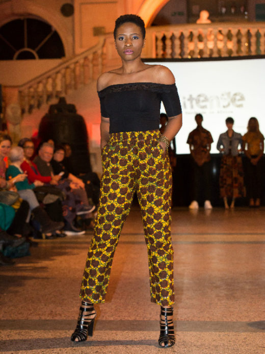 A model wearing a yellow giraffe African print trousers at the Fabric Africa Fashion Show in Bristol Museum UK