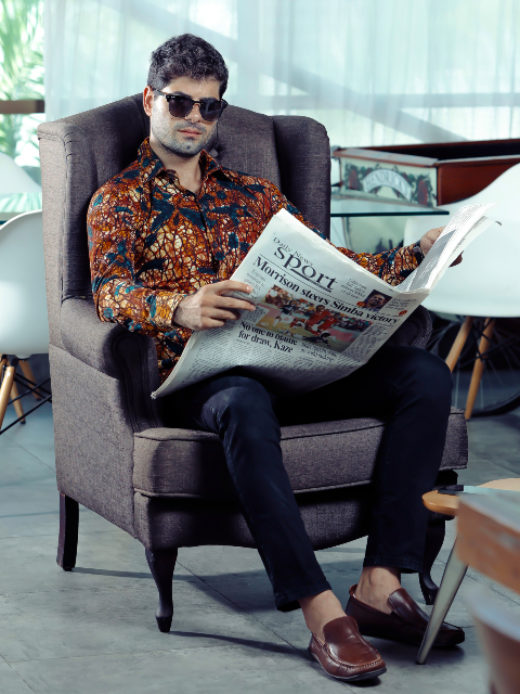 Men's gold floral custom-made African print long sleeve shirt model wearing reading newspaper in arm chair