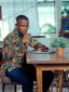 Men's green floral custom-made African print long sleeve shirt model wearing working sat down using laptop