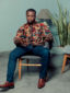 Men's red floral custom made African print long sleeve shirt model wearing sat down full outfit