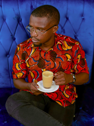 Men's red/yellow peacock custom-made African print short sleeve shirt model wearing sat down drinking tea