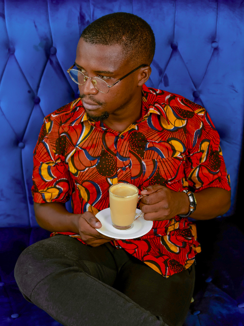Men's red/yellow peacock custom-made African print short sleeve shirt model wearing sat down drinking tea