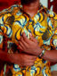 Men's yellow/white peacock custom-made African print short sleeve shirt model wearing front view closeup with arms