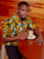 Men's yellow/white peacock custom-made African print short sleeve shirt model wearing front view sat down
