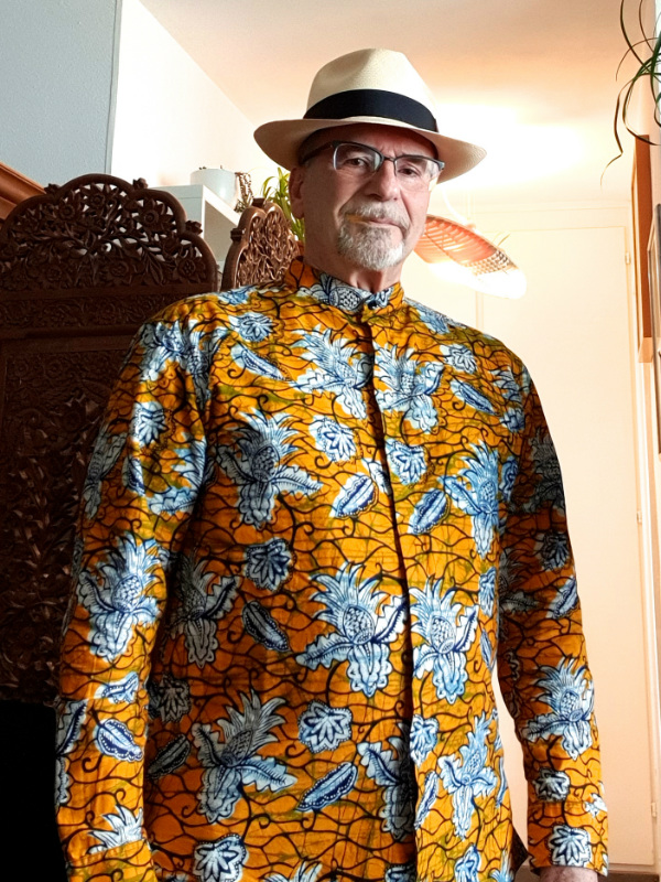 Kitenge Store customer from Switzerland modelling his yellow pineapple African print made to measure shirt with long sleeves mandarin collar and covered placket hidden buttons at home