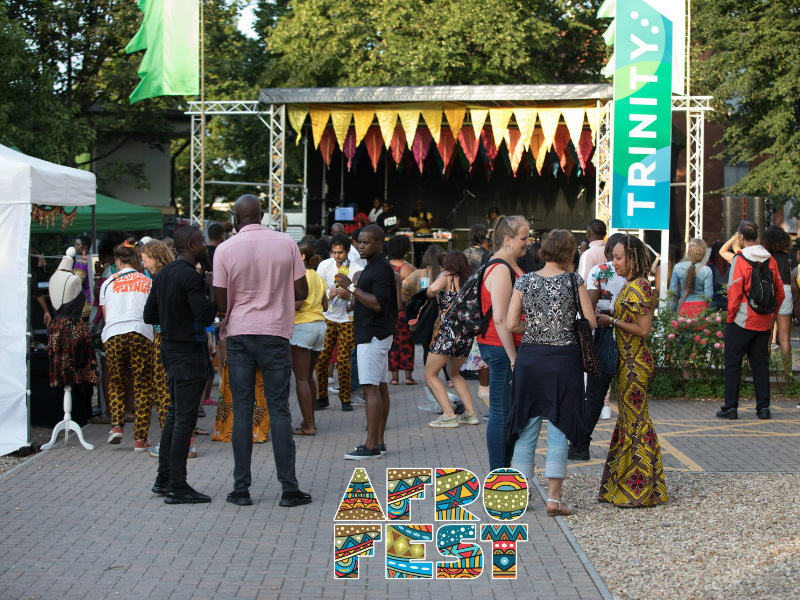 Kitenge stall in front of the main outdoor stage at AfroFest Bristol 2019 with visitors wearing African print clothing