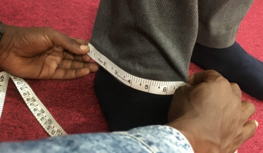 Measuring the ankle of a customer's trouser for tailor made clothing