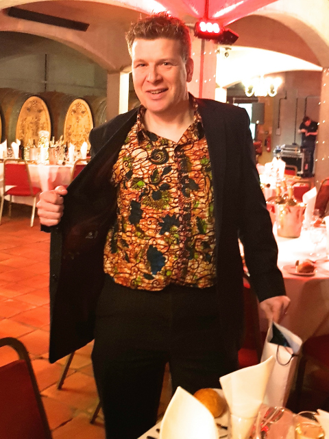Kitenge customer wearing their men's African print shirt at work event with black suit jacket and trousers