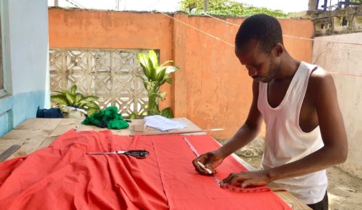 Kitenge African menswear tailor measuring fabric to make made to measure shirts in Tanzania East Africa
