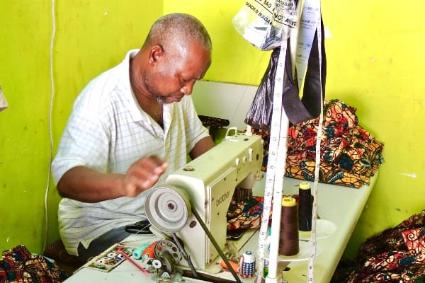 Kitenge master tailor sewing African print clothing at his workshop in Tanzania East Africa