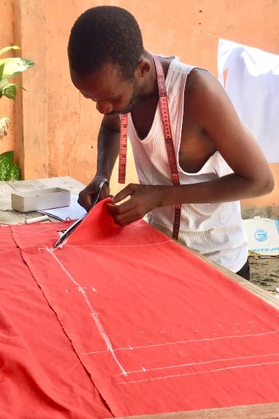 Kitenge Store African menswear tailor cutting fabric to make custom-made shirts in Tanzania East Africa