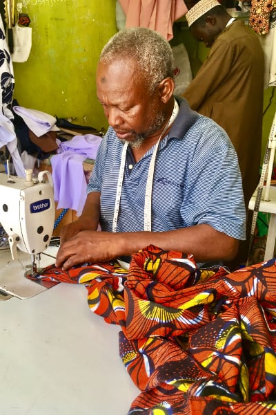 Kitenge master tailor making custom-made African print shirts for men in Tanzania