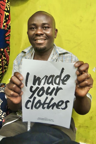 Kitenge African menswear tailor Hassan holding I Made your Clothes sign Fashion Revolution Week