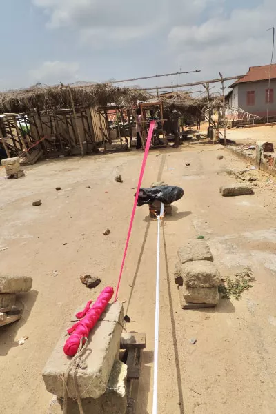 Warp thread placed under heavy stones during kente weaving production handloom Ghana West Africa