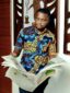 Men's yellow red blue flower African print shirt with short sleeves model wearing reading newspaper